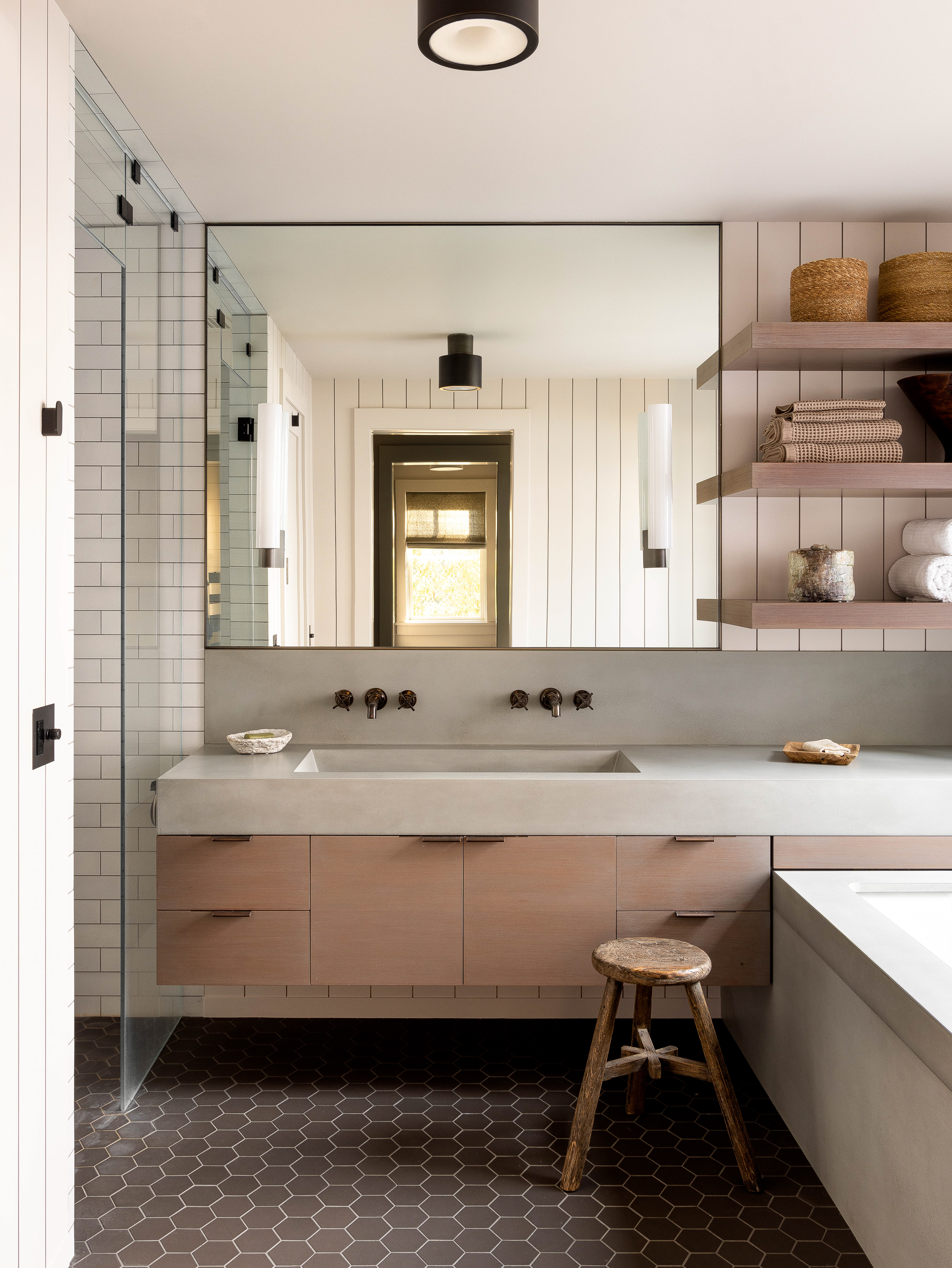 In a modest space, the spa-like primary bathroom features integrated vanity and tub, cedar cabinetry, and a large window with water views.